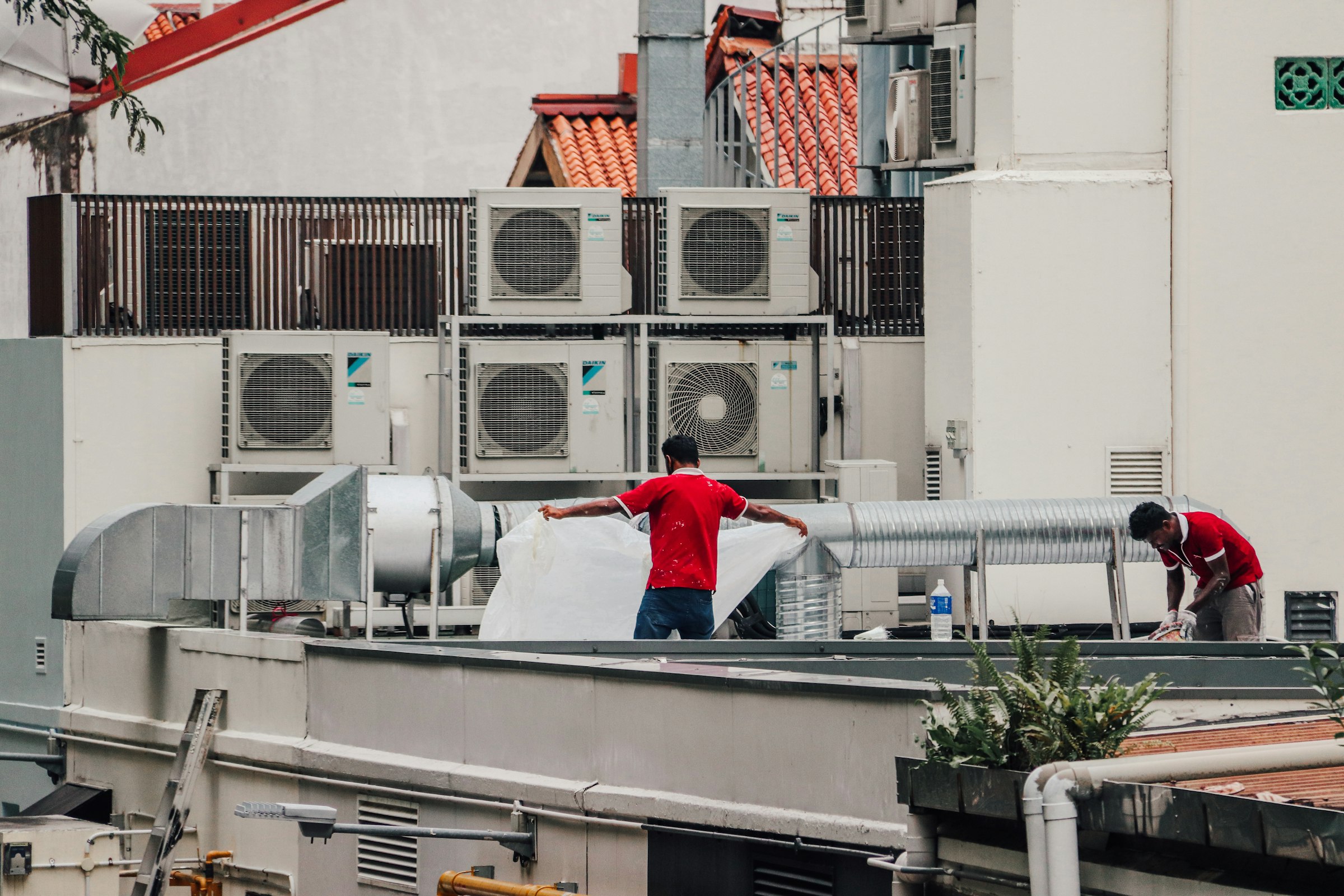 Two HVAC technicians servicing rooftop condenser units