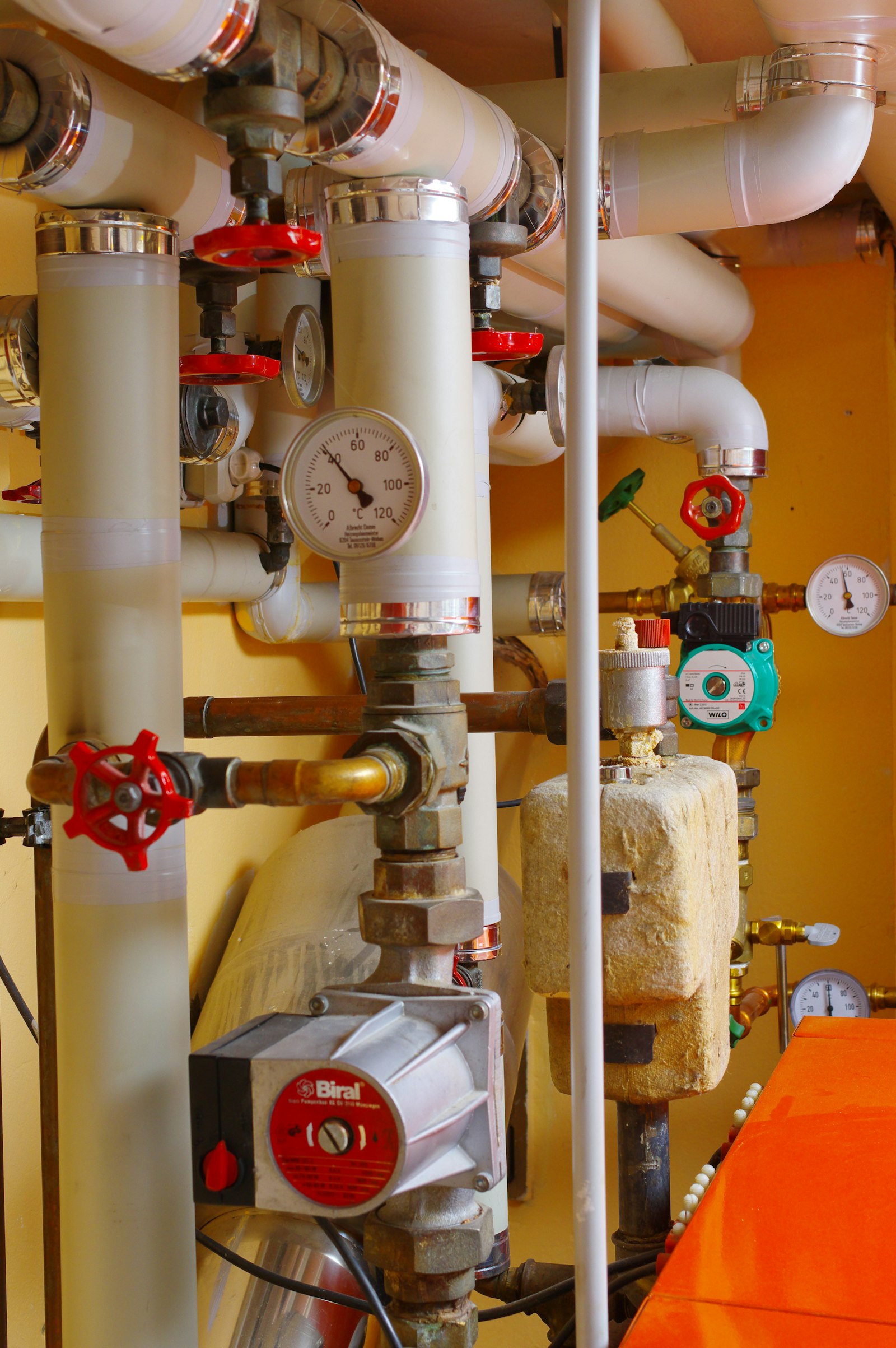 Mechanical room with heating pipes, valves, and pressure gauges
