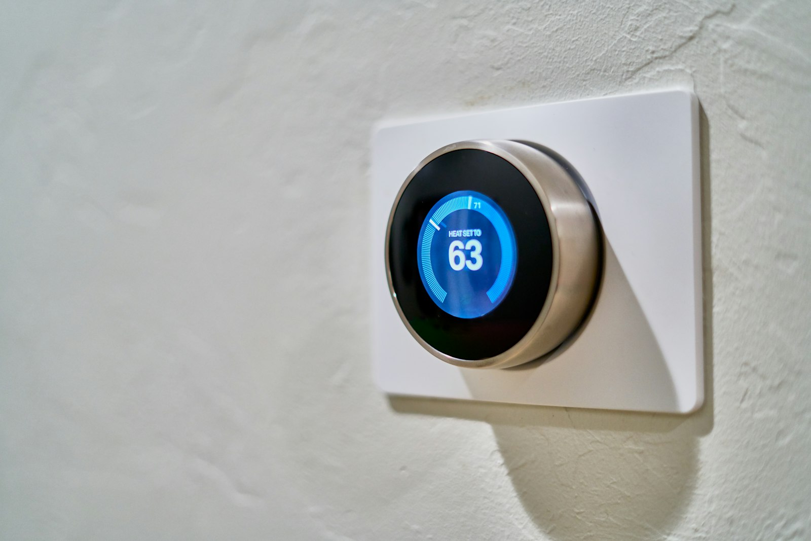 Smart thermostat mounted on a wall showing the heat setting